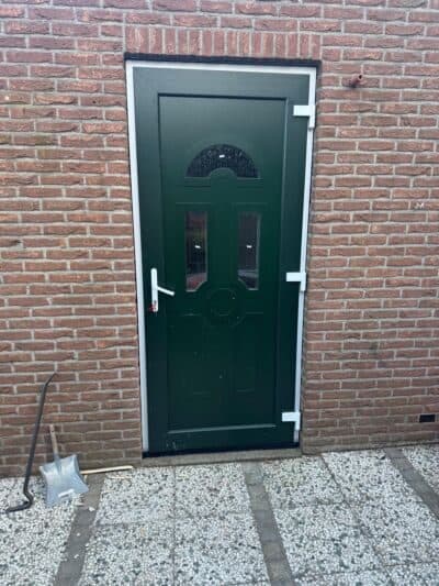 Donkergroene voordeur met glasdetail in een bakstenen gevel