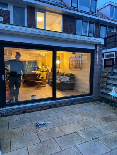 Schuifpui bij schemer met verlicht interieur en terras
